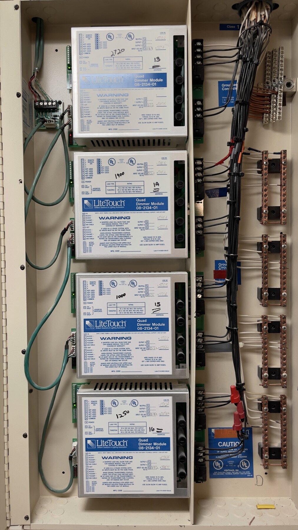 A LiteTouch panel with four Quad Dimmer Modules, each labelled by hand with its connected load in watts and its bus address