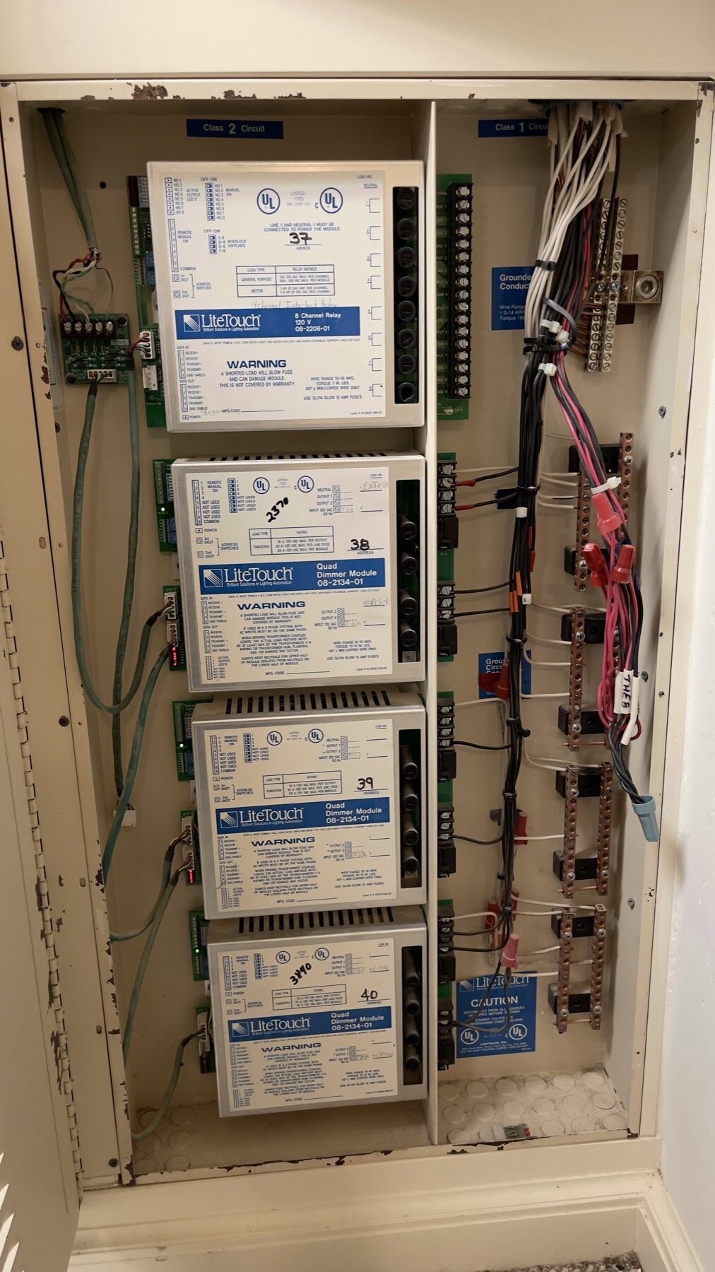 A LiteTouch enclosure with an 8 Channel Relay Module and three Quad Dimmer Modules, each marked by hand with its load and address