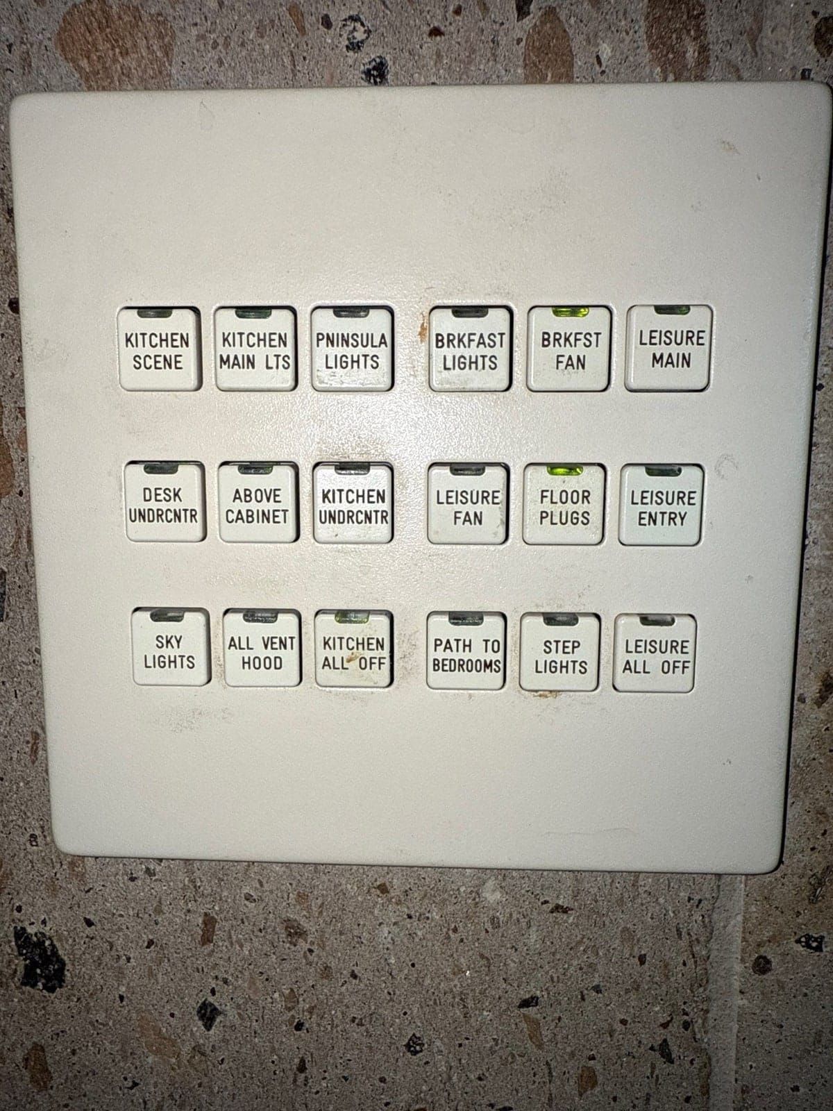 A LiteTouch keypad still in daily service in a Houston-area kitchen, its engraved buttons controlling scenes, fans and individual lighting circuits